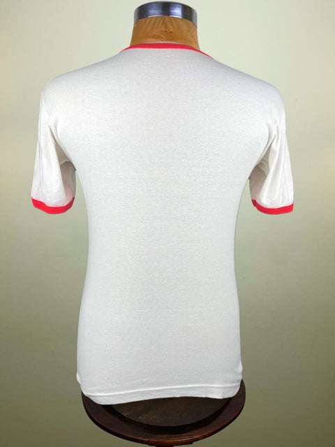 White shirt with red trim on a mannequin against a beige background