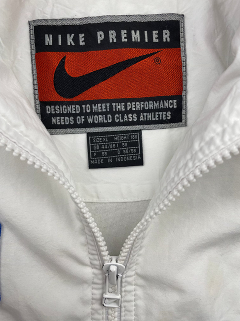Close-up of a Nike Premier label on a white jacket with a zipper.
