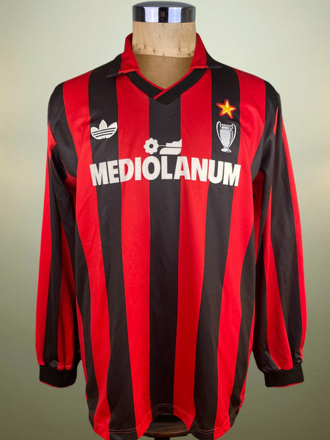 Red and black striped sports jersey with 'Mediolanum' and Adidas logos on a mannequin against a beige background.