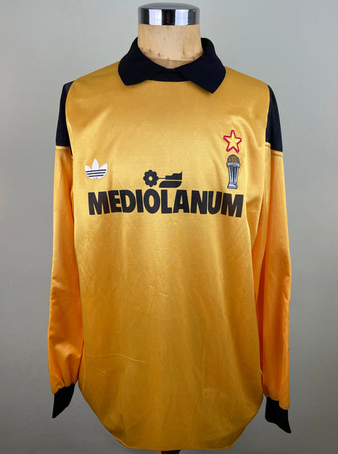 A long-sleeved AC Milan Goalkeeper soccer jersey with black text and graphics, including a logo on the chest and a star on the right chest area. The jersey is displayed on a mannequin with a visible brand tag.
