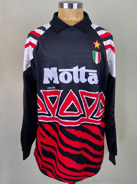 A short-sleeved soccer jersey with black, red, and white stripes, featuring text and a logo on the front.