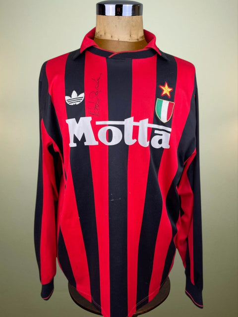 A jersey displaying the stripes and logo of AC Milan football club with a signature and the name 'Roberto Donadoni' on the back.