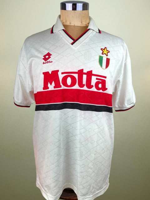 White AC Milan 1993-94 Away jersey with red and black details, sponsored by Motta and made by Lotto, on a mannequin against a beige background