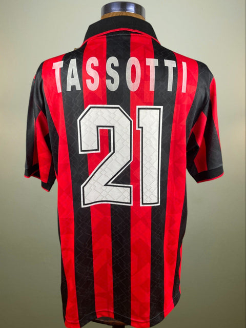 A red and black striped sports jersey with the name 'TASSOTTI' and the number '21' printed on the back.