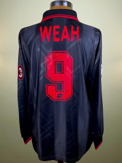 A black and red AC Milan soccer jersey with the name 'WEAH' and the number '9' on the back, signed and displayed on a mannequin.