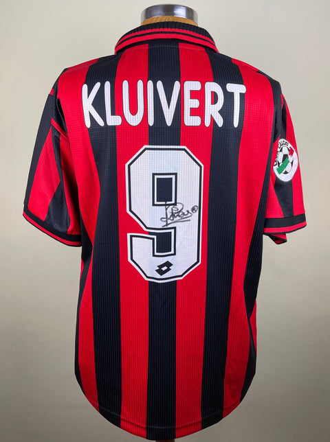 A short-sleeved soccer jersey with red and black stripes, number 9 on the back, and the name 'KLUIVERT' above it. The jersey is signed and has the AC Milan club crest.