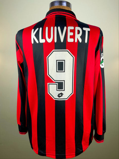 Red and black striped Milan jersey with 'Kluivert' and number '9' on a mannequin against a beige background