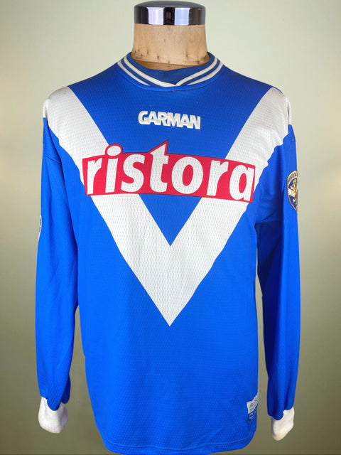 Blue Brescia jersey with 'Ristora' and 'Garman' logos on a mannequin against a neutral background