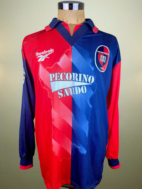 Red and blue Cagliari 1997-98 jersey with Reebok logo on a mannequin against a beige background