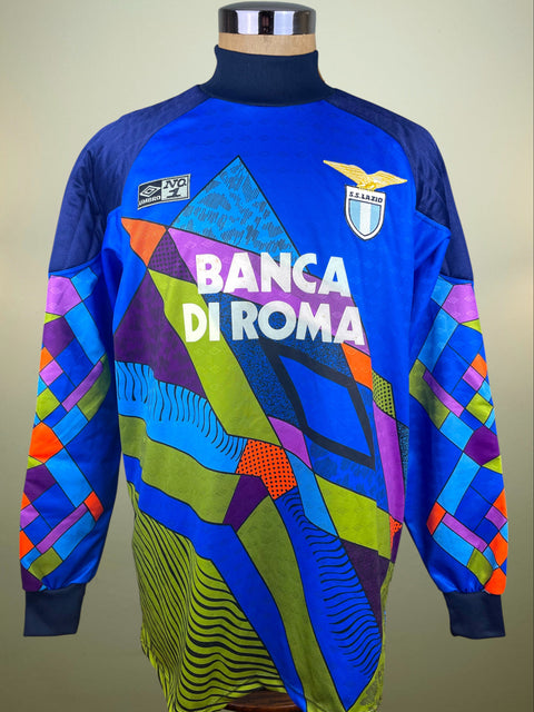 Colorful SS Lazio Keeper jersey with geometric patterns and 'Banca Di Roma' text on a mannequin against a neutral background.