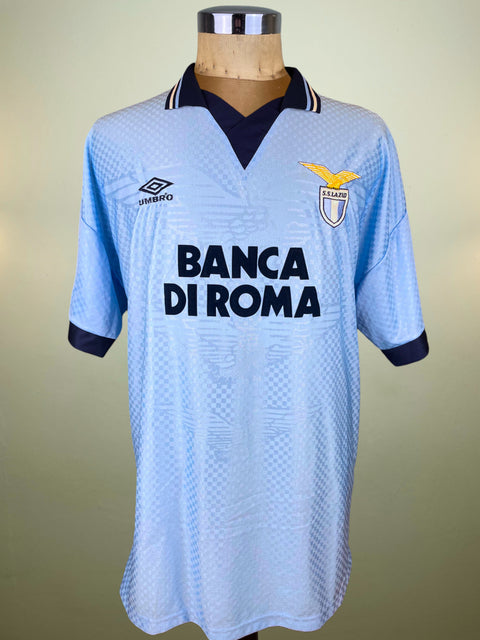 Light blue Lazio 1995 jersey with black Banca Di Roma Sponsor and Umbro logo on a mannequin against a beige background