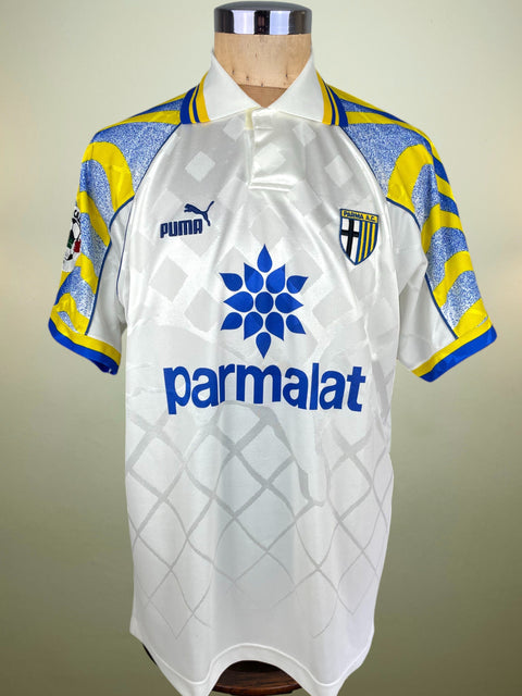 White match worn Hernan Crespo Parma home jersey from the 1996-97 season with blue and yellow accents on a mannequin, featuring Puma and Parmalat logos.