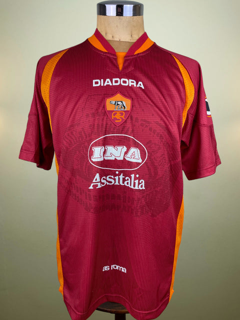 AS Roma 1997-98 sports jersey made by Diadora with orange accents on a mannequin against a beige background