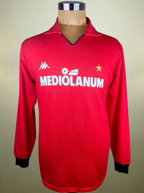 Red AC Milan jersey with 'Mediolanum' branding on a mannequin against a neutral background