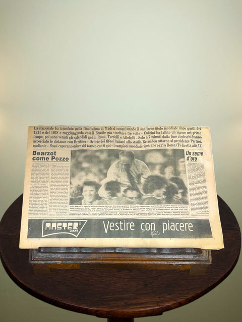Vintage newspaper titled 'La Gazzetta dello Sport' Celebrating Italy's 1982 World Cup win on a wooden stand with a light background