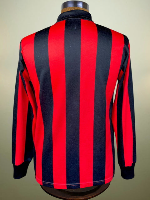 A long-sleeve striped sports jersey shown from the back on a mannequin torso. The jersey features bold vertical stripes in red and a very dark navy blue, with a high collar and ribbed cuffs.