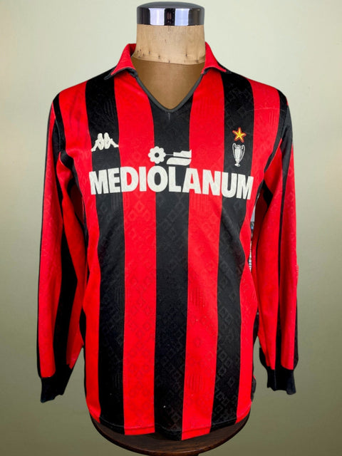 A red and black striped AC Milan soccer jersey from the 1989-90 season, displayed on a mannequin.