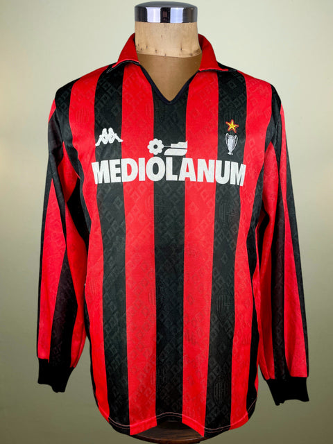 Red and black striped AC Milan jersey with 'Mediolanum' branding on a mannequin against a neutral background