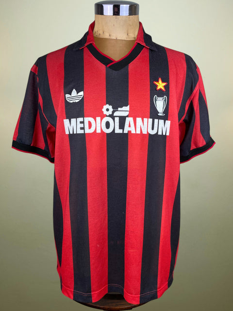 Red and black striped AC Milan 1990 jersey with Mediolanum and Adidas logos on a mannequin against a beige background, made with nido d'ape fabric.