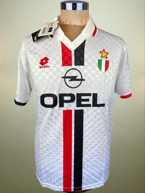 A vintage white AC Milan soccer jersey with red and black vertical stripes, featuring the Opel logo and Lotto brand mark, displayed on a wooden mannequin torso.