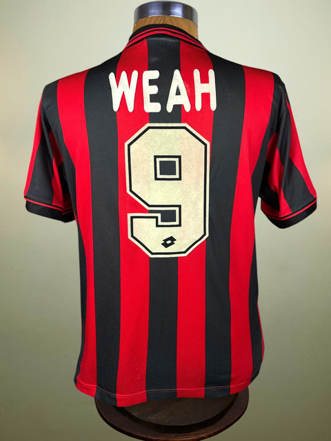 A vintage AC Milan home jersey with red and black vertical stripes, featuring 'WEAH' and the number '9' printed on the back in white and beige, displayed on a mannequin.