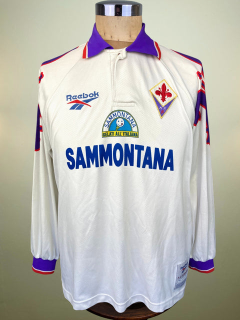 A vintage long-sleeve Reebok football jersey displayed on a mannequin torso. The white jersey features a purple collar, purple sleeve accents, and red trim.