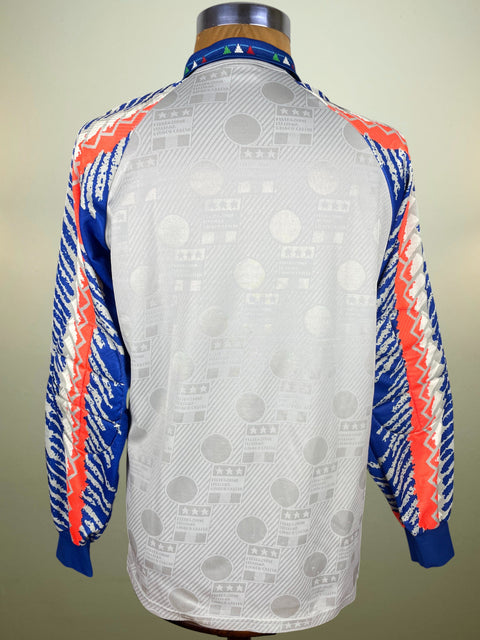 White Italy Goalkeeper jersey from World Cup 9 with blue and orange accents on a mannequin against a beige background