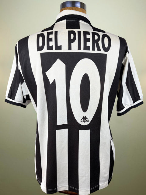 Back view of a black and white striped Juventus football jersey on a mannequin, featuring 'DEL PIERO' and the number '10' printed in white, with a small Kappa logo near the bottom.