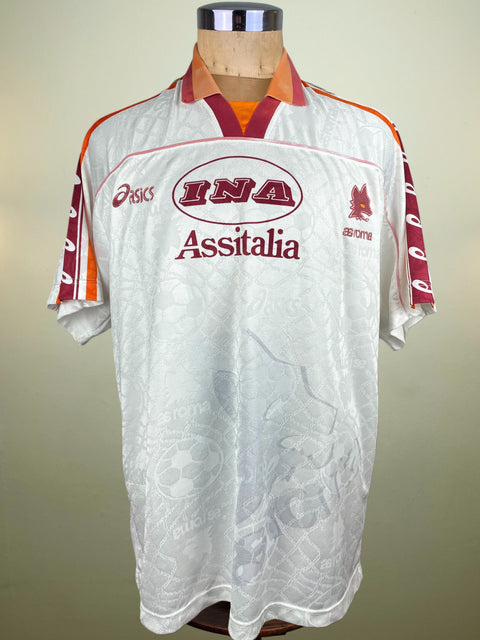 White AS Roma 1995-96 Away jersey with red and orange accents, made by Asics with INA Assitalia Sponsor on the chest on a mannequin against a beige background