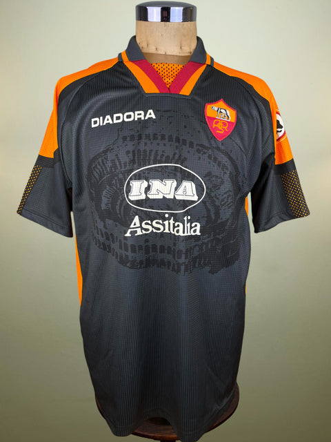 Black AS Roma jersey with orange accents on a mannequin against a beige background