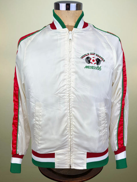 A white satin bomber jacket with red and green stripes on the sleeves, collar, and hem, featuring a 'World Cup Qualifiers Mexico 2006' crest on the left chest, displayed on a mannequin.
