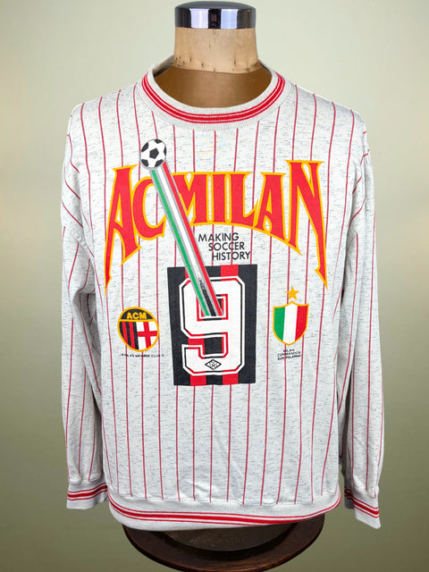 A long-sleeve AC Milan soccer jersey displayed on a mannequin torso. The jersey is light gray with thin red pinstripes and features a large front graphic with 'AC MILAN' in orange-red, a large black number 9, and club crests.