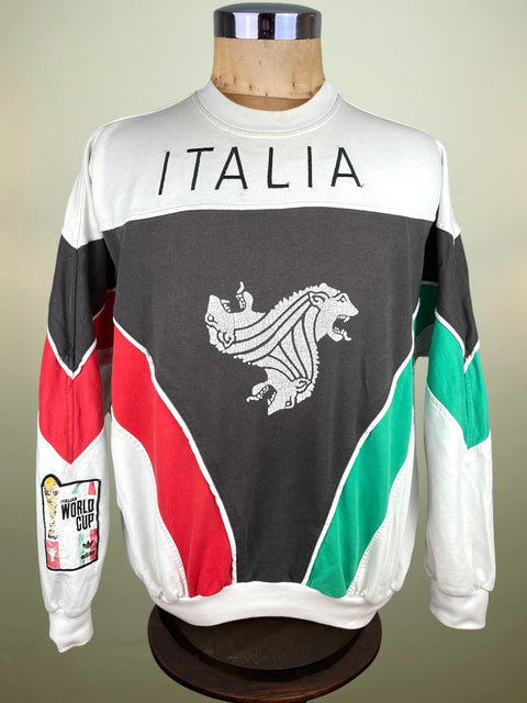 A long-sleeve crewneck sweatshirt displayed on a mannequin torso. The sweatshirt features a white, dark gray, red, and green color-blocked design with 'ITALIA' printed across the chest and a white stylized lion graphic in the center.