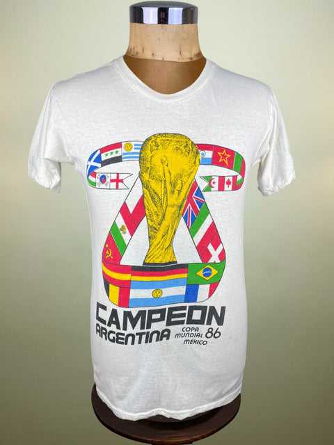 White t-shirt with World Cup trophy graphic on a mannequin against a beige background