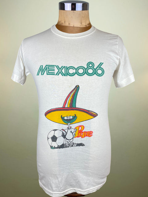 White t-shirt with 'Mexico 86' graphic design on a mannequin against a beige background