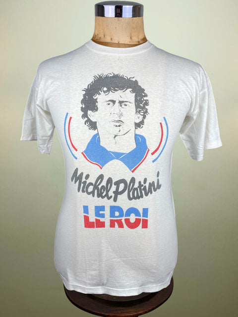 White t-shirt with a graphic of Michel Platini and text on a mannequin against a beige background