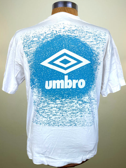 A white short-sleeve Umbro t-shirt displayed on a mannequin from the back, featuring a large distressed blue graphic with the white Umbro diamond logo and 'umbro' text.