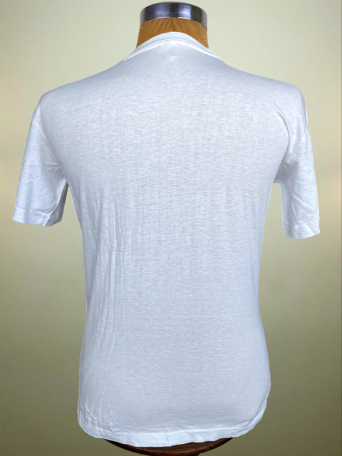 A white short-sleeve t-shirt displayed on a wooden dress form mannequin, showing the back view against a light beige gradient background.