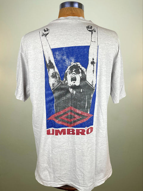 Gray t-shirt with a graphic design on the back featuring a person and Umbro logo, displayed on a mannequin.