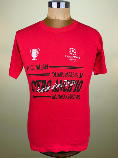 A red short-sleeve graphic T-shirt displayed on a mannequin torso against a plain light beige background. The shirt features white and black printed text and logos, including 'A.
