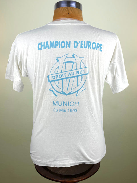 White t-shirt with blue text and graphics on a mannequin against a beige background