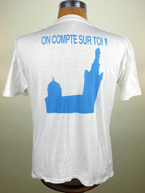 White t-shirt with blue graphic and text on a mannequin against a neutral background
