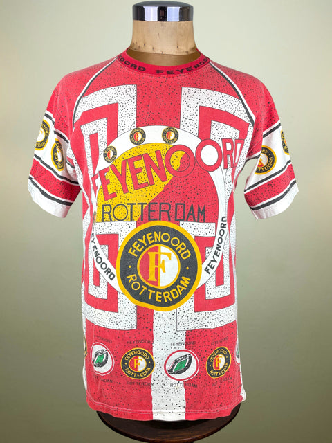 Red and white sports jersey with Feyenoord Rotterdam branding on a mannequin against a beige background.