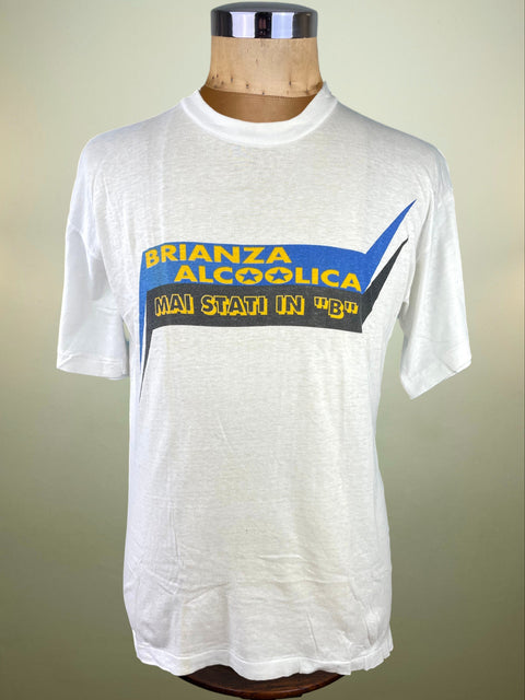 White t-shirt with blue and yellow text on a mannequin against a beige background