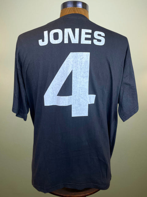 Back view of a dark navy blue short-sleeve t-shirt displayed on a wooden dress form. The shirt features the name 'JONES' and the number '4' printed in a light gray or off-white distressed font.
