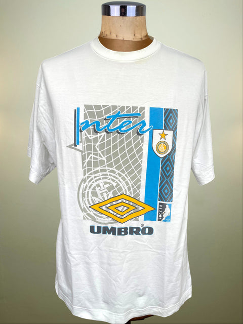 A white Umbro Inter Milan soccer t-shirt displayed on a wooden dress form mannequin. The shirt features a large front graphic with blue, yellow, and gray elements, including the Inter Milan club crest and the Umbro logo.