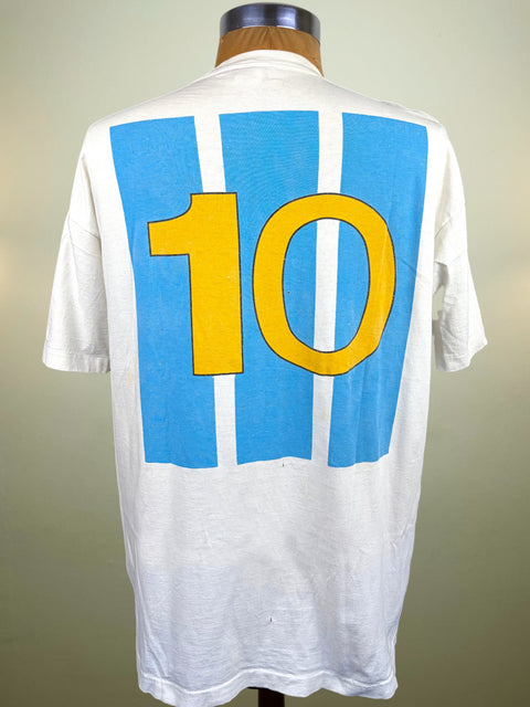 A white short-sleeve t-shirt displayed on a mannequin from the back, featuring a large graphic of blue and white vertical stripes with a bold yellow number 10.