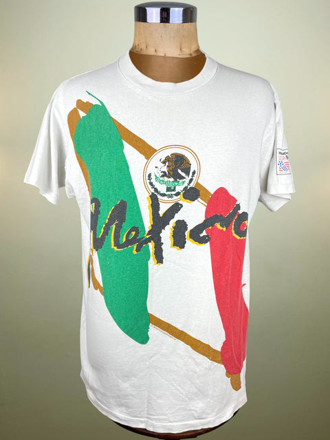 White t-shirt with Mexican flag design on a mannequin against a neutral background