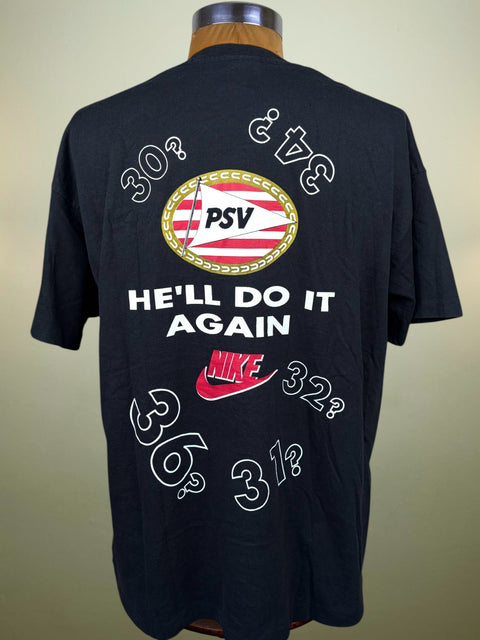 A black short-sleeve t-shirt displayed on a mannequin torso, showing the back graphic. The design features a circular red, white, and gold PSV crest, the text 'HE'LL DO IT AGAIN' in white, a red Nike swoosh, and white numbers like 30, 32, 36, 34, 3 1/2 in a stylized outline font.