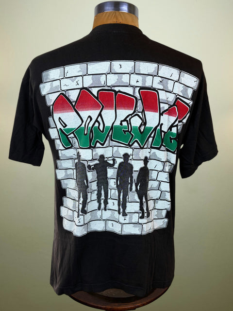 A black short-sleeve t-shirt displayed on a wooden dress form, showing the back graphic. The graphic features a white brick wall design with the word 'Nevig' in stylized graffiti letters filled with the Hungarian flag colors (red, white, and green).